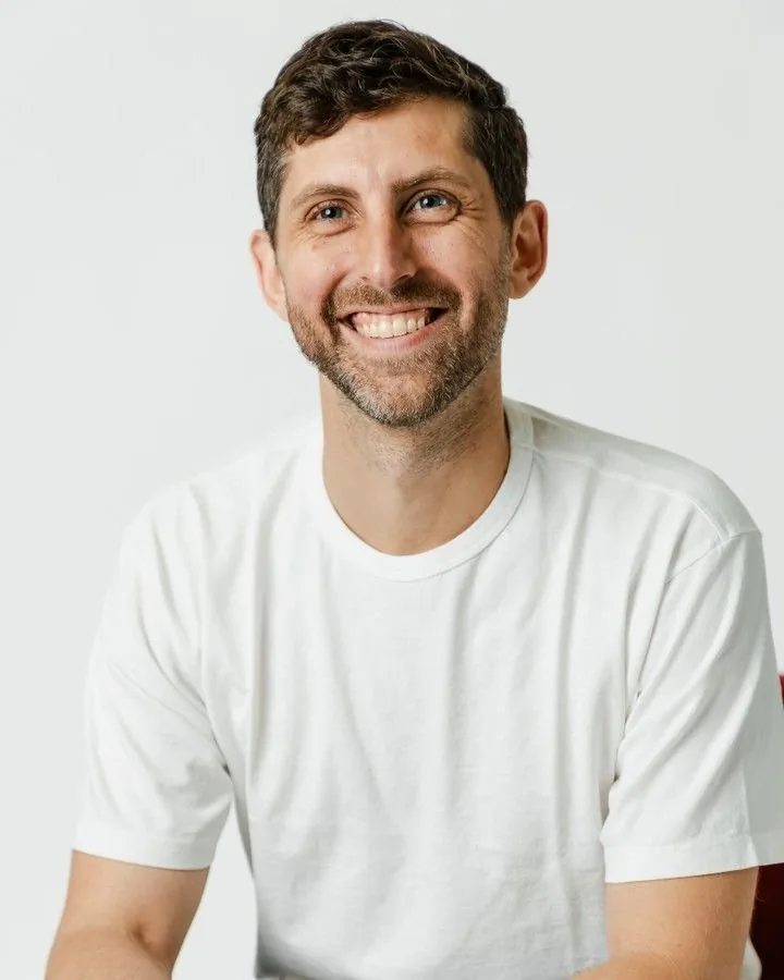 Homme souriant en t-shirt blanc, portrait net sur fond clair