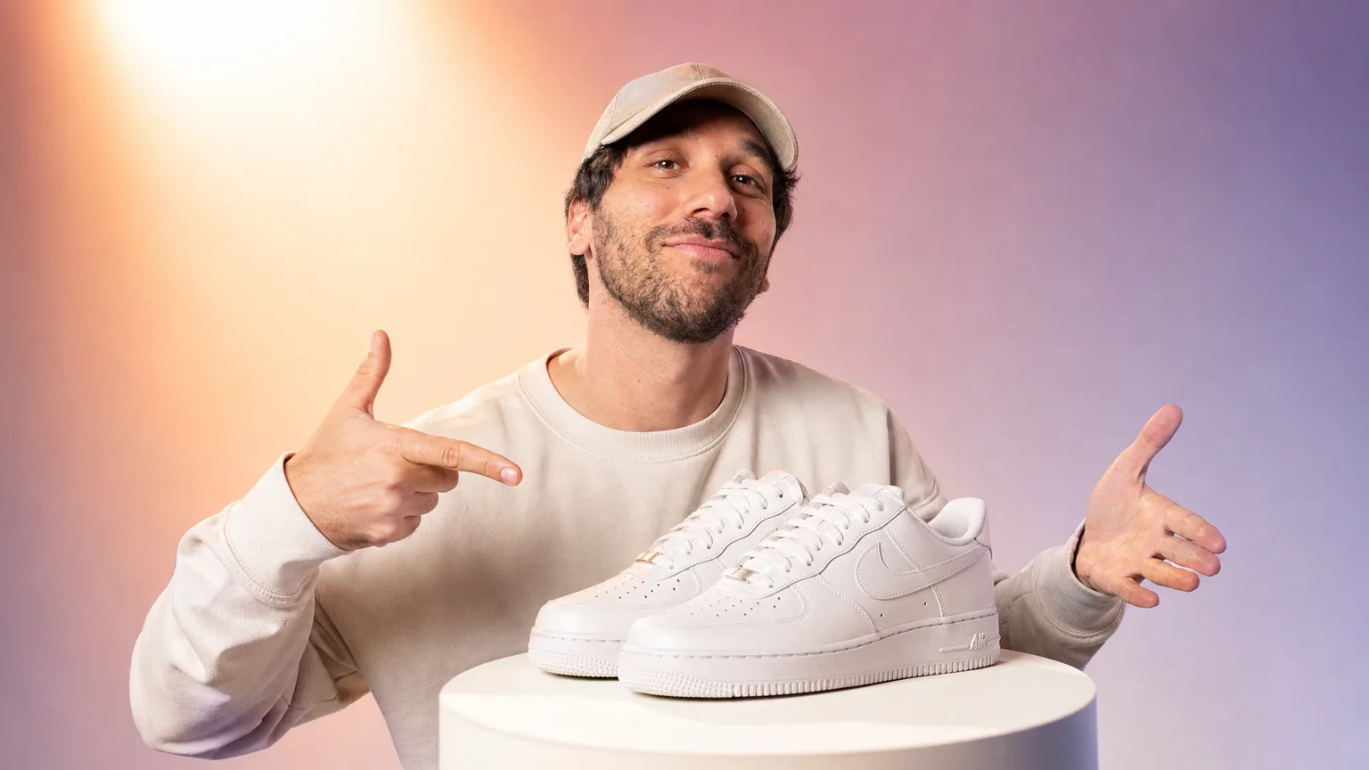 Ismael présente une paire de baskets blanches posée sur un socle