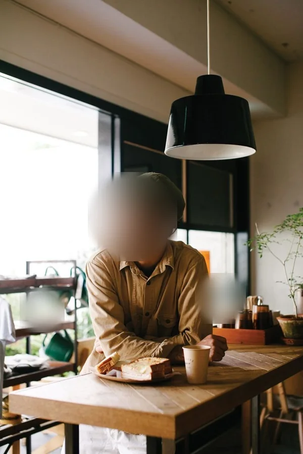 La scène de la bibliothèque&nbsp;: un homme à la table d'un café, près de la vitrine, visage flouté