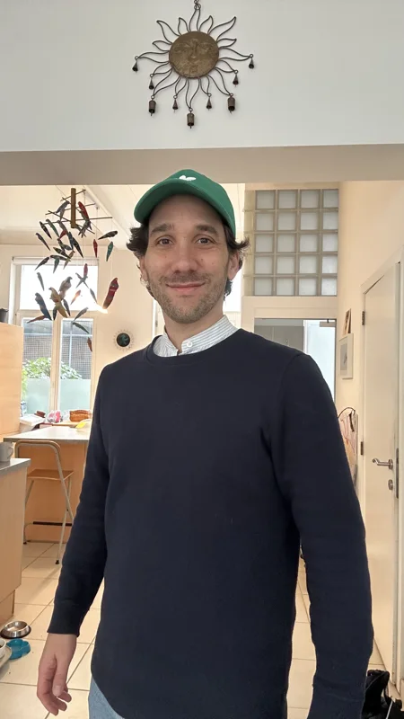Ismael, debout chez lui, casquette verte