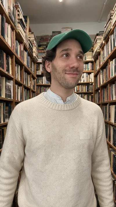 La retouche : la même pose entre les rayons d'une librairie, pull en maille écrue